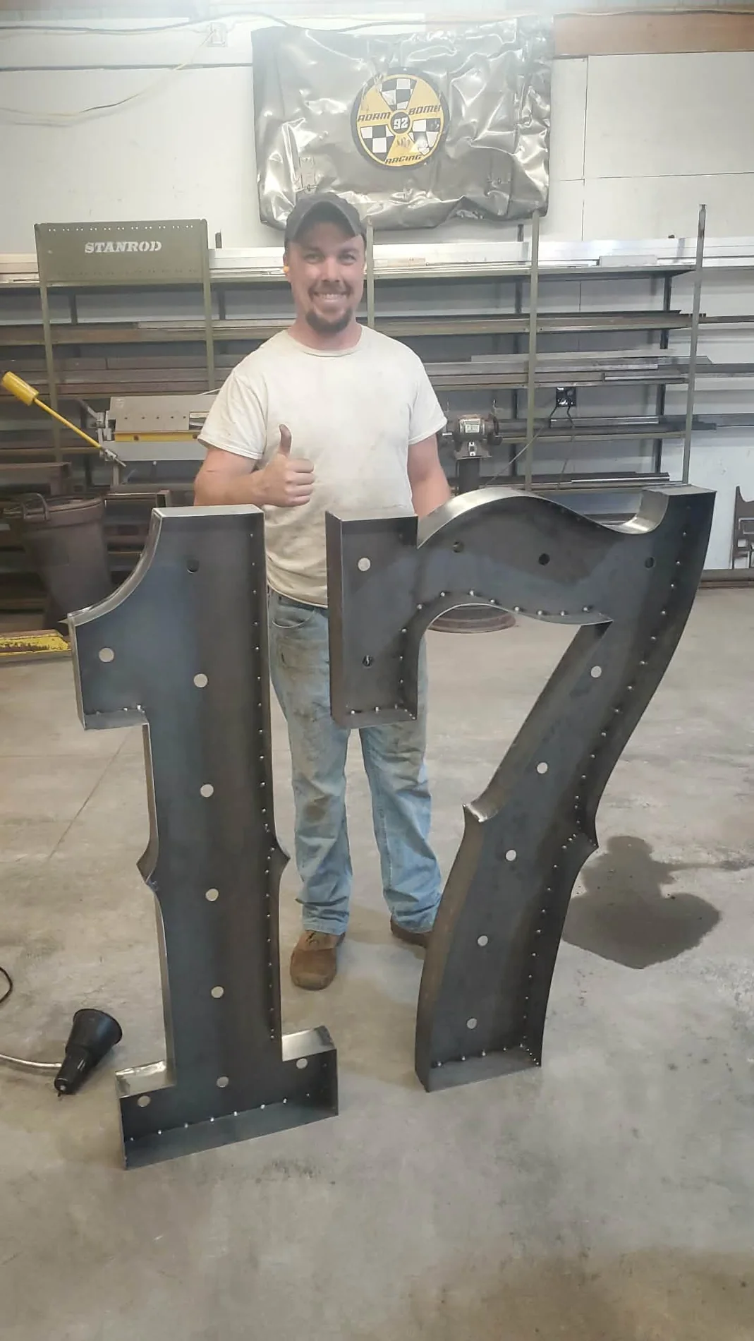 Adam Stanfill standing with a giant custom number 17 fabricated for the Wildcatter Suite at War Memorial Stadium